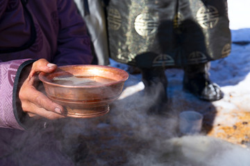 Mongolian national tea in a copper bowl in hands