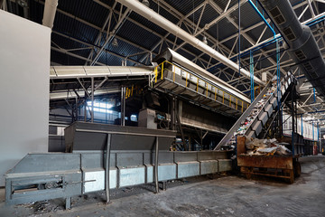 Conveyor belt at recycling plant transports garbage inside drum filter or rotating cylindrical...
