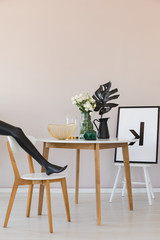 Black mannequin's leg on wooden chair in elegant dining room interior with copy space on the empty wall
