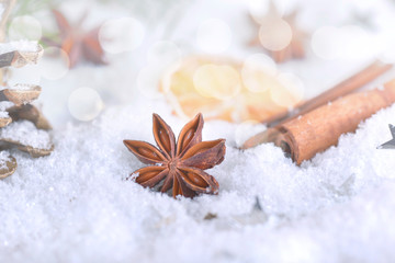 Obraz na płótnie Canvas anise star and cinnamon on snow and lights christmas decoration