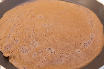 Chocolate pancake close-up on a hot pan