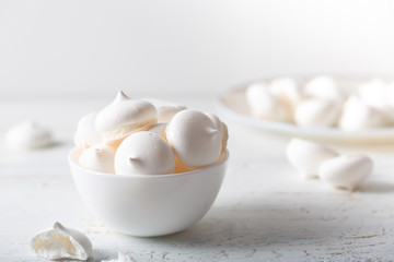 Meringues dessert on white wooden table, side view