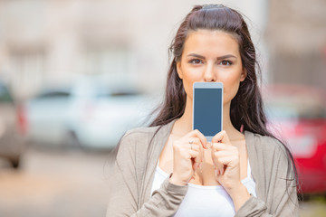 Fototapeta premium Cute young woman using cellphone in urban surroundings.