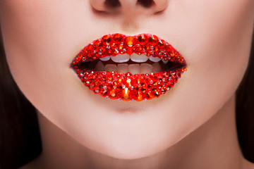 Red lips covered with rhinestones. Beautiful woman with red lipstick on her lips - obrazy, fototapety, plakaty