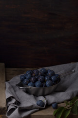 Fototapeta na wymiar Blue blackthorn or sloe berries on the white bowl