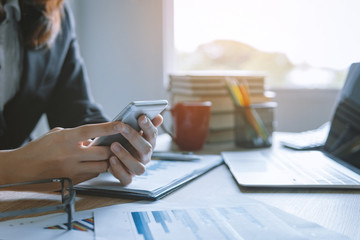 business women working using smart mobile phone and laptop with finance graph at office workplace desk. business technology concept.