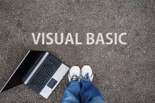 man legs in sneakers standing next to laptop and words Visual Basic, programming language