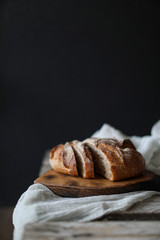 Bread at wood board with napkin on dark background