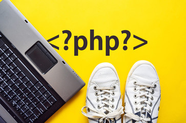man legs in shoes standing next to laptop and php tag on yellow background