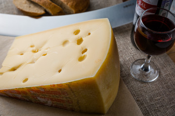 Composition of big piece of cheese and bottle of wine on a dark background