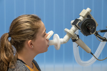 A young asthmatic girl having a lung function test.