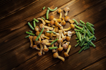 Frozen wild mushrooms and green beans on a wooden natural background