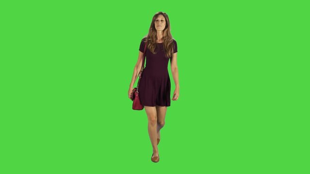 A young woman walking towards camera, goofing around in a full body shot over a green screen.