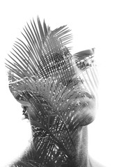 Double exposure of a young sexy man’s portrait blended with branches of a tropical palm tree, showing the perfect beauty of nature's creation in black and white
