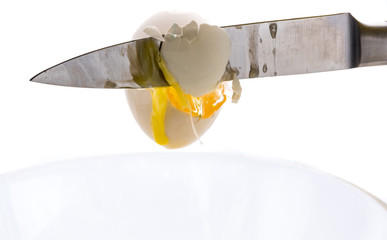 The falling egg breaks on the blade of a knife
