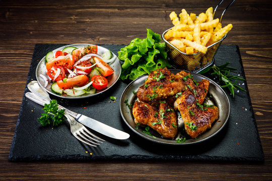 Roast chicken wings with french fries and vegetable salad 