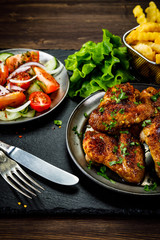 Roast chicken wings with french fries and vegetable salad 