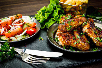 Roast chicken wings with french fries and vegetable salad 