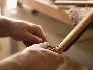 luthier is working on the neck of a classical guitar.