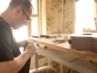 luthier is working on the neck of a classical guitar.