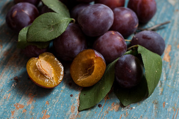 Plum slices and whole old blue wooden background.