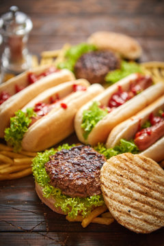 Fastfood assortment. Hamburgers and hot dogs placed on rusty wood table. Served with french fries. View from above.