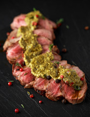 Medium rare venison steak with green pesto sauce and pepper
