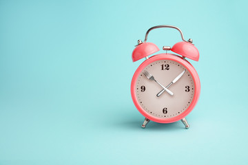 Alarm clock. Fork and knife instead of clock hands. Concept of intermittent fasting, lunchtime,...