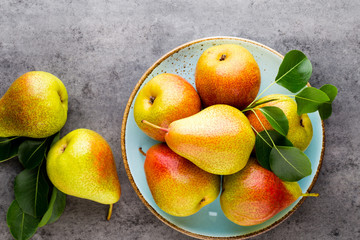 Fresh bio pear with leaves on the plate. Gray stone table.