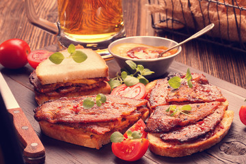 Beef sandwich with herbs and tomato on wooden board
