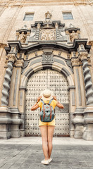 Fototapeta na wymiar Asian woman traveler with backpack and hat standing at the old vintage door entrance