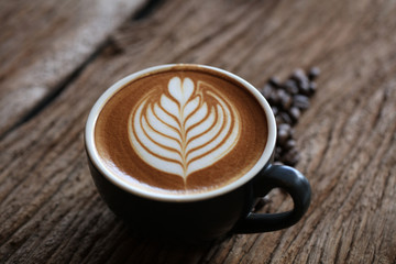 Hot cappuccino coffee dressing with leave shape of latter art, coffee latte art on wood table flat lay