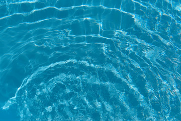 Round waves in the clear blue water of swimming pool