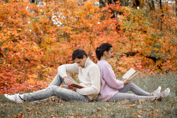 couple in love sitting in autumn park and reading book