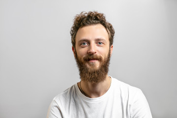 Fototapeta premium Portrait of young handsome hipster man with beard smiling at camera having positive, kind and confident look, promissing that client have made a right choice, isolated over white background.