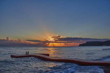 Dawn on the sea with light waves and a curved pontoon