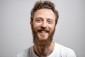 Portrait of young handsome softie, good-looking kind hipster man with beard smiling and looking at...