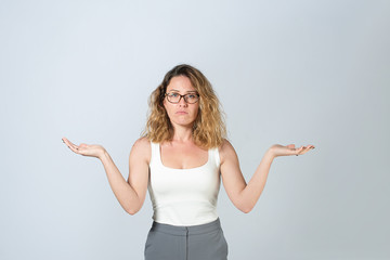 Young business woman in a white T-shirt and gray pants. beautiful lady with glasses spread her arms to the side. on gray background