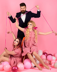 Obraz na płótnie Canvas Crazy girls and man on pink. Halloween. Creative idea. Love triangle. retro girls and master in party balloons. vintage fashion women puppet and man. holidays and dolls. dominance and dependence