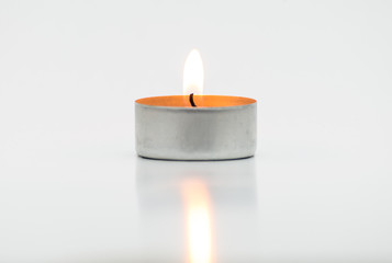 Burning paraffin candles, tealight, lies on a white background with a clipping path.