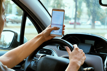 Naklejka premium women's hands on the wheel with the phone