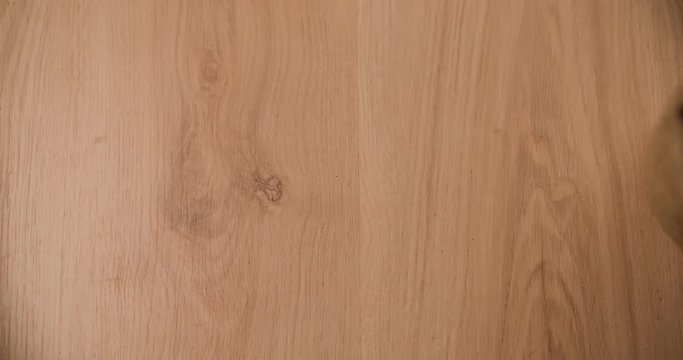 Bag falling and scattering coffee beans on wood table surface top view Slow motion video