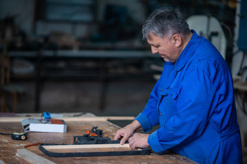 Assembling the wooden frame on the carpentry table in workshop with glue and different tools