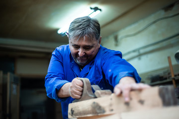 carpenter working in workshop, a worker planing a tree with a planer