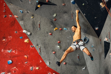 Shortless athletic man bouldering at indoor climbing centre. climber practicing rock climbing at an indoor climbing gym. © alfa27