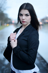young woman standing in the rain near a river