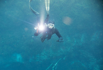 Spearfishing man with flashlight in deep of lake looking to the camera