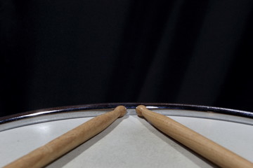 Wooden Drum Sticks Sitting On Snare Drum against a dark background