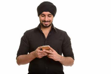 Young happy Indian Sikh using mobile phone
