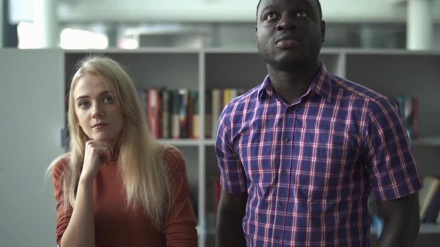 European woman and african american choose a book in the library